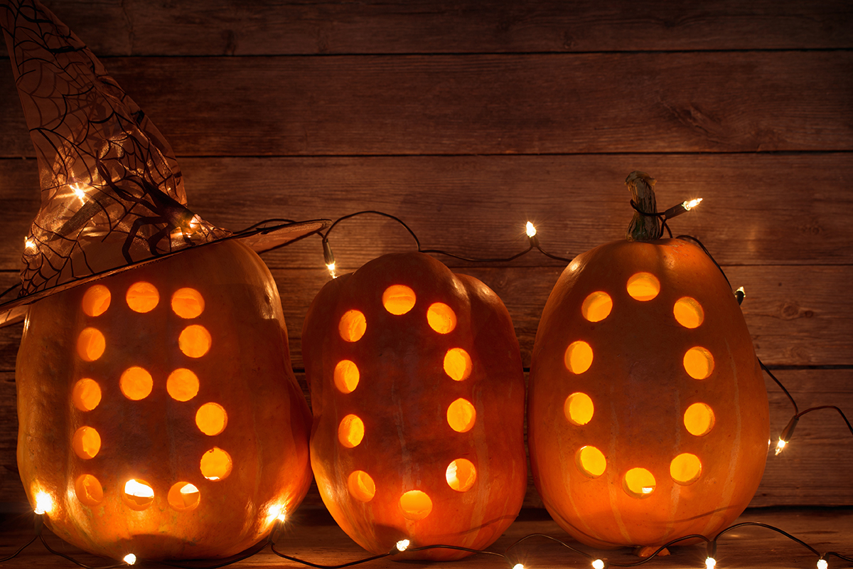 Three lighted pumpkins carved with the letters 'BOO"